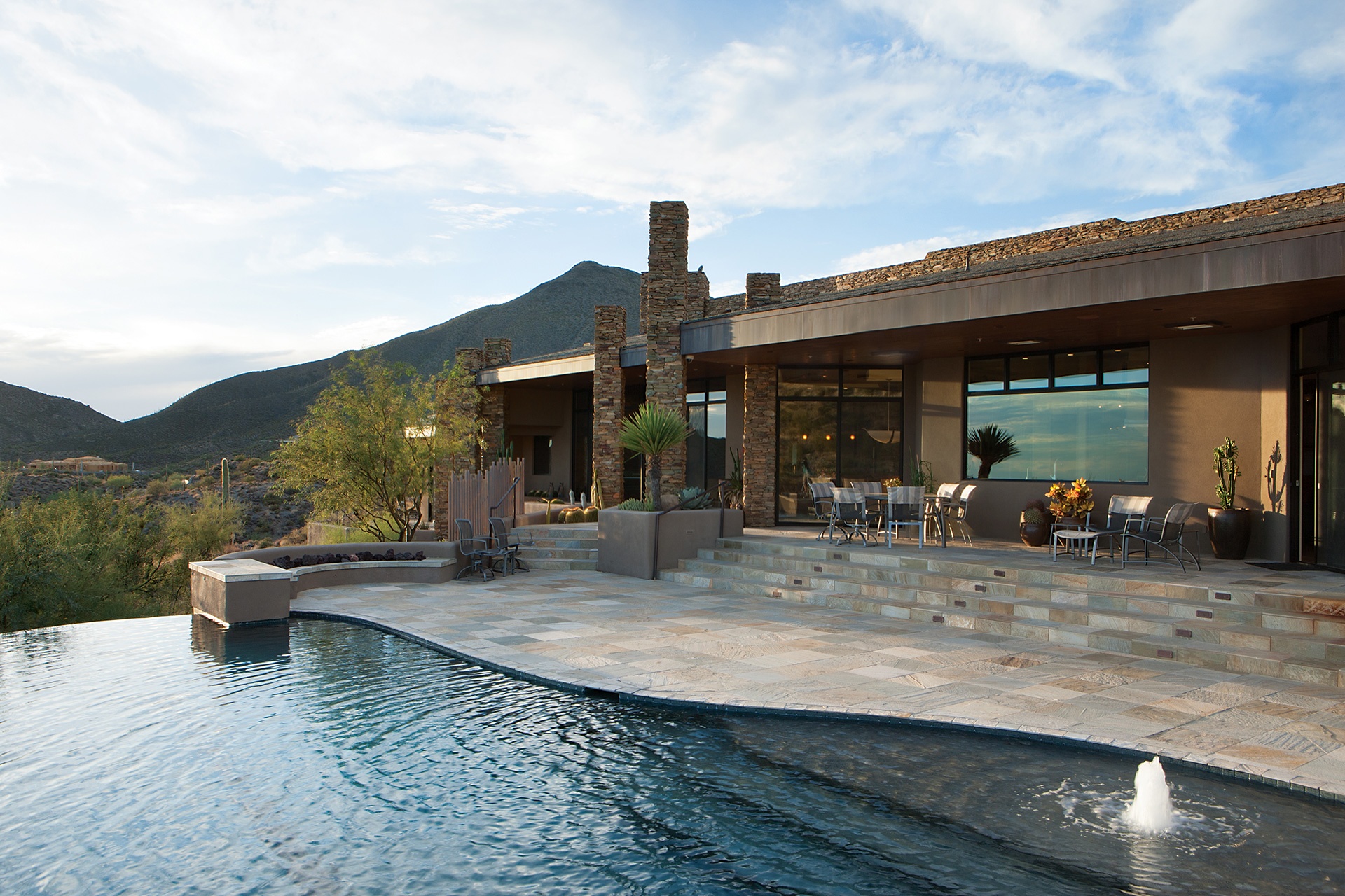 At one with its magnificent setting in the Sonoran Desert, this contemporary retreat features a covered dining terrace with mountain, city light, and sunset views. 